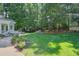 Lush green backyard featuring mature trees, a stone patio, and a charming storage shed at 575 Valley Hall Dr, Sandy Springs, GA 30350
