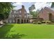 A large backyard featuring verdant grass and an elegant brick home with an arched covered patio at 2671 Bohler Nw Rd, Atlanta, GA 30327
