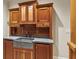 Wet bar featuring natural wood cabinetry, a farmhouse sink, granite countertops, and antique style fixtures at 2671 Bohler Nw Rd, Atlanta, GA 30327