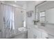 Bright bathroom featuring a shower-tub combo with floral curtain, decorative mirror, and a marble-top vanity at 414 Concord St, Alpharetta, GA 30009