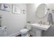 This bathroom showcases a pedestal sink, round mirror, and framed floral artwork, creating a refreshing and stylish space at 414 Concord St, Alpharetta, GA 30009