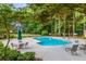 A community pool area nestled in a lush wooded setting, with ample lounge chairs and umbrella-covered tables at 6487 Northridge Way, Morrow, GA 30260