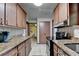 Galley kitchen featuring granite countertops, wood cabinets, tile flooring and modern black appliances at 8805 Lake Dr, Snellville, GA 30039