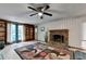 Cozy living room with a brick fireplace, built-in shelving, and a decorative ceiling fan at 8805 Lake Dr, Snellville, GA 30039