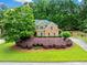 Beautiful brick home featuring an expansive green lawn, mature landscaping, and a circular driveway at 205 Camden Creek Ct, Lawrenceville, GA 30043