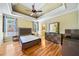 Spacious bedroom with tray ceiling, ceiling fan, hardwood floors, and ensuite bathroom access at 205 Camden Creek Ct, Lawrenceville, GA 30043