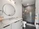 Stylish bathroom boasts a modern vanity, a round mirror, and a sleek glass-enclosed shower with gray tile at 2297 Nesbitt Ne Dr, Brookhaven, GA 30319