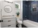 Modern bathroom with blue tiled shower, white vanity, black hardware and fixtures, and a sleek round mirror at 2297 Nesbitt Ne Dr, Brookhaven, GA 30319