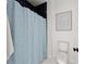 Modern bathroom features a blue shower curtain, white toilet, and art for simple elegance at 2297 Nesbitt Ne Dr, Brookhaven, GA 30319