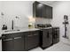 Modern laundry room features dark cabinetry with marble countertops, sink, washer, dryer, and cleaning supplies at 2297 Nesbitt Ne Dr, Brookhaven, GA 30319