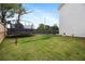 Fenced backyard with lush green grass, a trampoline, and a basketball hoop for Gathering fun at 437 Autrey Dr, Douglasville, GA 30134