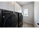 Modern laundry room with front-loading washer and dryer, upper cabinets, and a window at 437 Autrey Dr, Douglasville, GA 30134