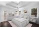 Well-lit main bedroom featuring a tray ceiling, large windows, and a stylishly decorated queen-sized bed at 7025 Bavarian Wood Pl, Buford, GA 30518