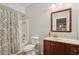 Well-lit bathroom features a bathtub with shower, toilet and cherry wood vanity with ample counter space at 3099 Hidden Falls Dr, Buford, GA 30519