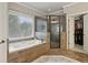 A well-lit bathroom showcasing a soaking tub, a glass-enclosed shower, and a walk-in closet at 3099 Hidden Falls Dr, Buford, GA 30519