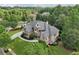 Beautiful aerial view of a large brick home with a circular driveway, surrounded by mature trees and green landscaping at 3099 Hidden Falls Dr, Buford, GA 30519