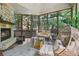 Cozy sunroom features a stone fireplace, hanging chairs, screened windows, and outdoor views at 3099 Hidden Falls Dr, Buford, GA 30519