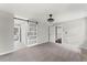 Spacious bedroom featuring modern lighting, carpet, and a sliding barn door at 5254 Greenpoint Drive, Stone Mountain, GA 30088