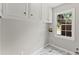 Functional laundry room with upper cabinets, tile flooring, and a window at 5254 Greenpoint Drive, Stone Mountain, GA 30088
