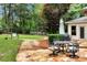 A serene backyard scene showcasing a stone patio with dining set, manicured lawn, and privacy provided by mature trees at 1320 Northcliff Trce, Roswell, GA 30076