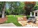 Landscaped backyard featuring a stone patio with dining set, a well-kept lawn, and a charming stone pathway at 1320 Northcliff Trce, Roswell, GA 30076