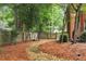 View of backyard landscaping with stone path, mulch, wooden fence, and mature trees at 1320 Northcliff Trce, Roswell, GA 30076