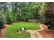 A well-manicured backyard with a lush green lawn, stone pathway, mature trees, and privacy shrubs at 1320 Northcliff Trce, Roswell, GA 30076
