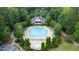 Aerial view of a large community pool with a clubhouse, wading pool, and comfortable seating, surrounded by trees at 1775 Porterton Way, Cumming, GA 30041