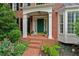 Close-up of the front entrance with brick steps, a green door, and decorative plants at 1775 Porterton Way, Cumming, GA 30041