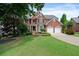 Charming two-story red brick home with lush green lawn, mature trees, and a two-car garage at 1775 Porterton Way, Cumming, GA 30041