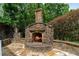 Outdoor stone fireplace with hearth and chimney offering cozy outdoor ambiance on stone patio at 1775 Porterton Way, Cumming, GA 30041