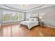 Elegant main bedroom with hardwood floors, tray ceiling, decorative chandelier, and natural light at 1775 Porterton Way, Cumming, GA 30041