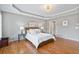 Elegant main bedroom featuring a tray ceiling, hardwood floors, and ambient lighting fixtures at 1775 Porterton Way, Cumming, GA 30041