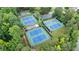 Aerial view of the neighborhood tennis and basketball courts surrounded by mature trees and lush landscapes at 1775 Porterton Way, Cumming, GA 30041