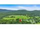 Aerial view showing the property's proximity to fields and rolling, wooded mountains at 33 Moriah Ne Way, Rydal, GA 30171