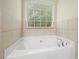 Close-up of a pristine white bathtub with elegant chrome fixtures, set against a backdrop of tiled walls and a window at 2774 Birch Grove Se Ln # 11, Marietta, GA 30067