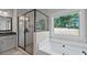 Bathroom features walk-in shower, soaking tub, and large window with backyard view at 902 Edgewater Dr, Loganville, GA 30052