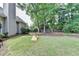 Large grassy backyard with mature trees and partial fencing on a sunny day at 1635 Lake Heights Cir, Dacula, GA 30019