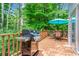 Outdoor deck with gas grill, table and chairs, and an umbrella, surrounded by lush greenery and landscaping at 1605 Spinnaker Drive, Alpharetta, GA 30005