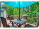 View of table and chairs with blue umbrella over outdoor deck with lush landscaping at 1605 Spinnaker Drive, Alpharetta, GA 30005