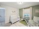 Bedroom with green accent wall, crib, and neutral rug at 5077 Martindale Ln, Stone Mountain, GA 30088