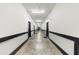 Long hallway with neutral walls and flooring leads to stairwell with black trimmed doors and baseboards at 5300 Peachtree Rd # 1608, Chamblee, GA 30341