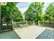 Spacious wooden deck with a railing overlooks a backyard with lush green trees and playground equipment at 1122 Cayuga Ct, Dacula, GA 30019