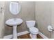 Compact powder room with a pedestal sink, rounded mirror and modern fixtures at 1122 Cayuga Ct, Dacula, GA 30019