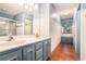 Bathroom with double sink vanity, framed mirrors, tiled shower, and wood accent wall and flooring at 1488 White Columns Blvd, Canton, GA 30115