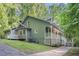 Charming home with a long, covered porch, lush greenery, and a convenient side entry garage at 1488 White Columns Blvd, Canton, GA 30115