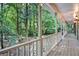 Covered front porch with white railing overlooking beautiful landscape of mature trees at 1488 White Columns Blvd, Canton, GA 30115