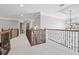 Upstairs hallway features carpeted floors and decorative wrought iron railing with chandelier in background at 1754 Water Springs Way, Dacula, GA 30019