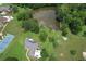 Scenic aerial shot of a property featuring a house, tennis court, lush greenery, and a serene pond at 5690 Rutland Trce, Lithonia, GA 30058