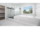 Bathroom featuring a glass shower and soaking tub with a backyard view for relaxation at 5690 Rutland Trce, Lithonia, GA 30058